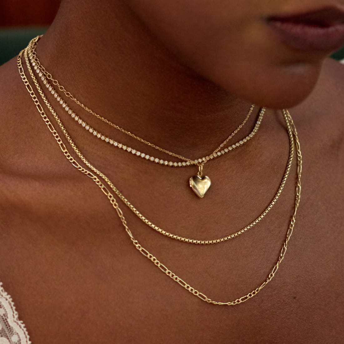 A close-up of a person's neck featuring multiple layered necklaces with colorful beads in red, blue, pink, and black.