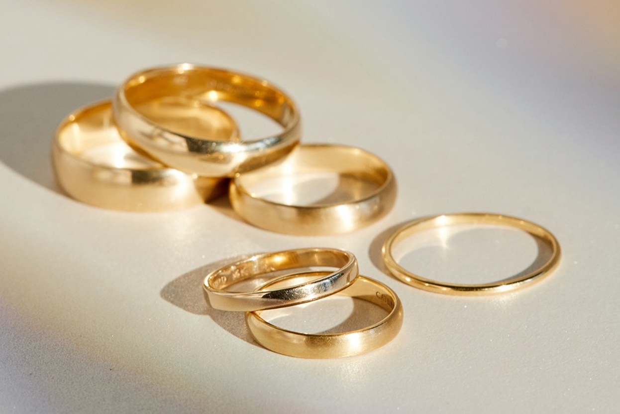Close-up of an ear with multiple gold piercings: a large hoop, a star stud, a twist design, a small stud, and a diamond-shaped stud. Warm lighting adds a stylish, elegant tone.